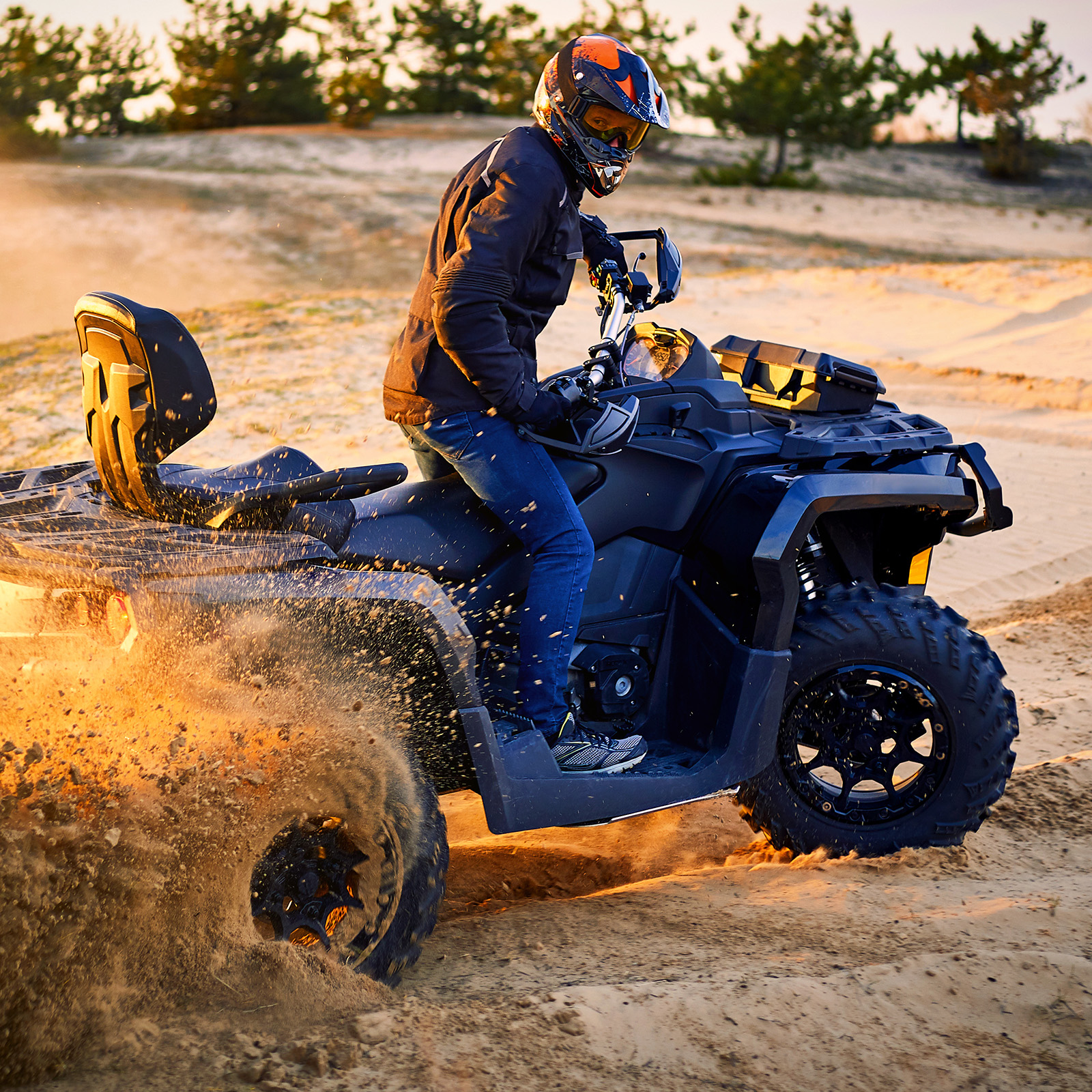 ATV riding across loose sand with deep tread visible on the wheels